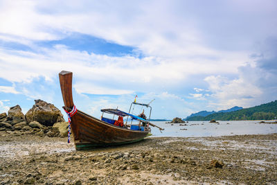 Boat moored on beach against sky