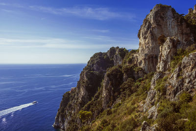 Scenic view of sea by cliff against sky