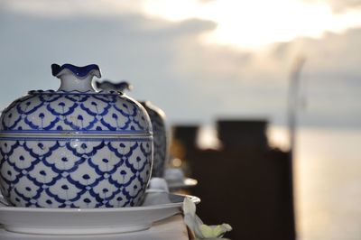 Close-up of porcelain container on table against sky during sunset