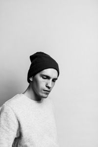 Thoughtful young man standing against white background