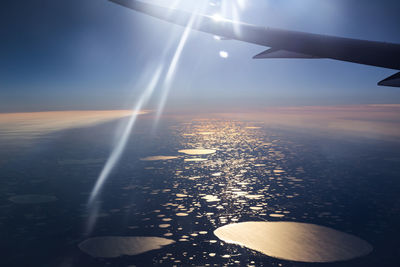 Cropped image of airplane flying over sea on sunny day