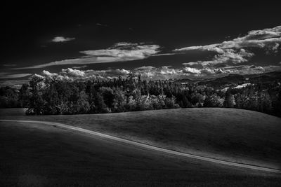 Road amidst trees and landscape against sky
