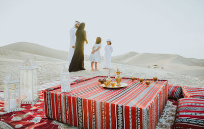 Family standing by carpet on sand dune