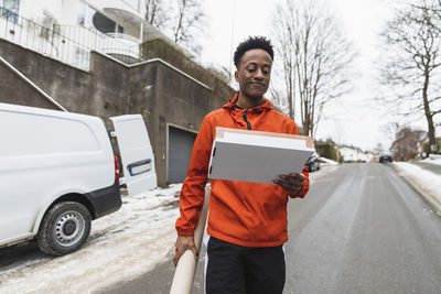 Young delivery man carrying packages while walking on road