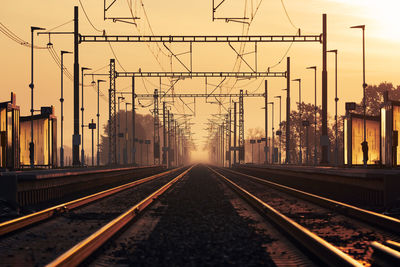 Surface level of railroad tracks against sky during sunset