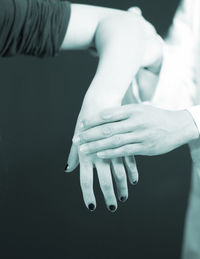 Midsection of doctor examining hand against black background