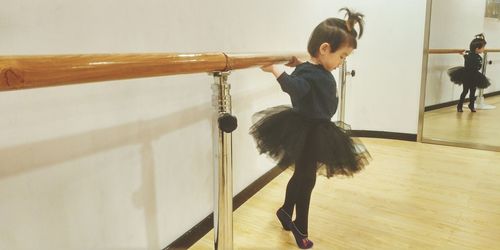 Side view of girl in tutu practicing tiptoe on hardwood floor