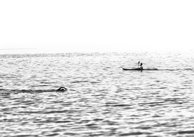 Man swimming in sea against clear sky