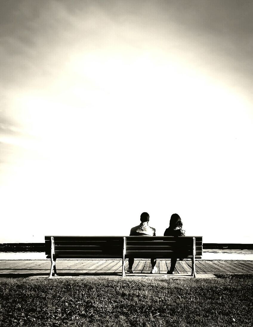 REAR VIEW OF PEOPLE SITTING ON BENCH