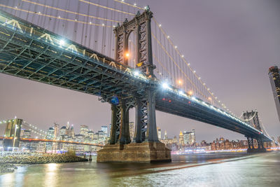 Illuminated bridge over river at night