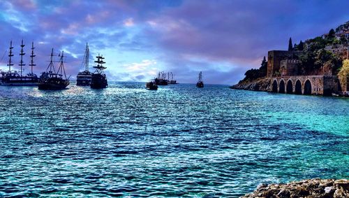 Boats in sea against cloudy sky