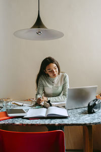 Young woman looking at laptop while doing homework