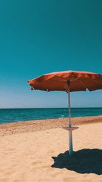 Parasol at beach against clear sky