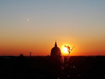 Silhouette temple against building during sunset