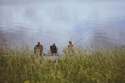 Rear view of people fishing in water