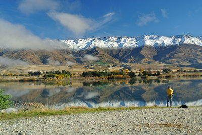 Rear view of man standing by calm lake