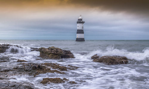 Lighthouse by sea against sky