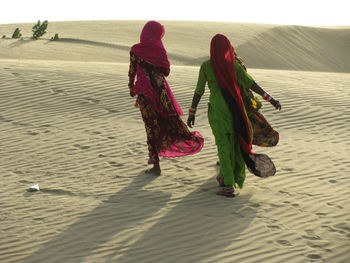 Rear view of women on sand at beach