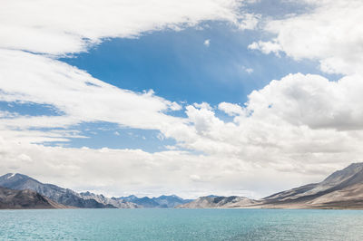 Scenic view of pangong lake by mountains against cloudy sky