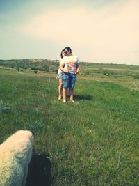 Full length of young woman with dog standing on field