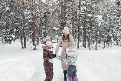 Mother with two daughters walks in a snowy forest on her day off. high quality photo