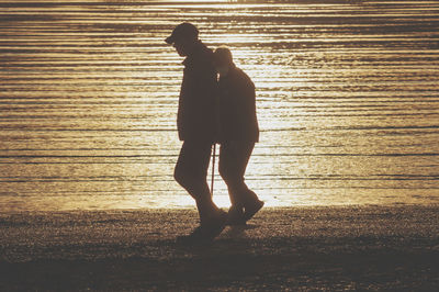 Silhouette man standing on beach during sunset