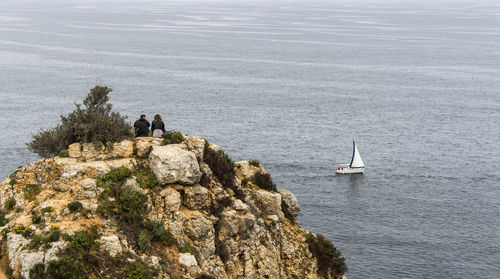 Rear view of people on cliff against sea