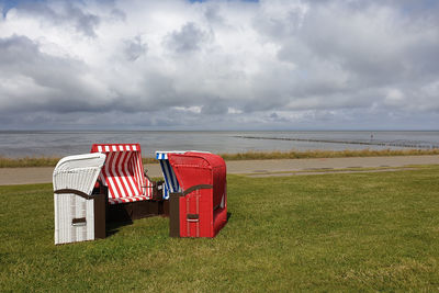 Red chairs on beach against sky