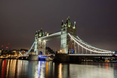 Illuminated bridge over river against sky at night