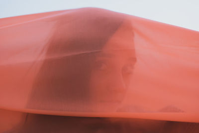 Close-up of woman seen through orange textile