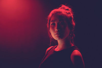 Close-up portrait of young woman against black background