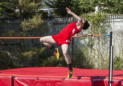 Full length of man jumping on red umbrella