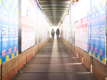 Rear view of people walking in passageway