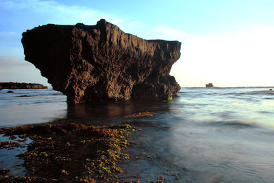 Rock formation on beach against sky