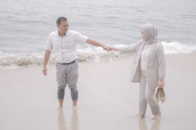 Full length of couple holding hands at beach