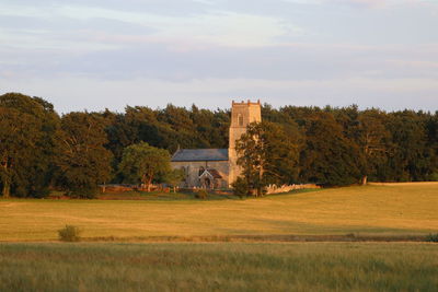 Church behind golden fields of wheat at the golden hour