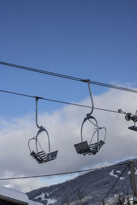 Low angle view of ski lift against blue sky