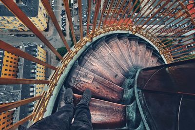 Low section of man standing on spiral staircase in city