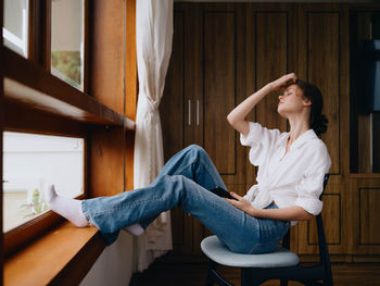 Side view of young woman looking through window