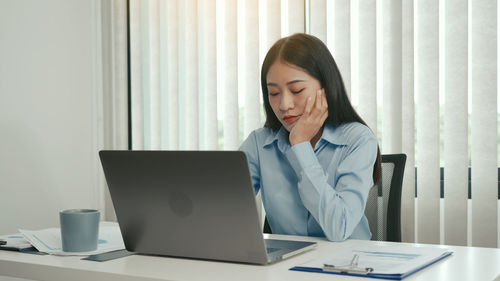 Young woman using mobile phone while sitting on table