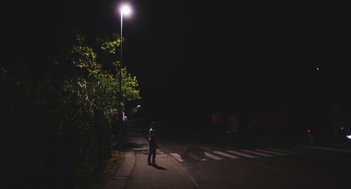 Man walking on illuminated street at night