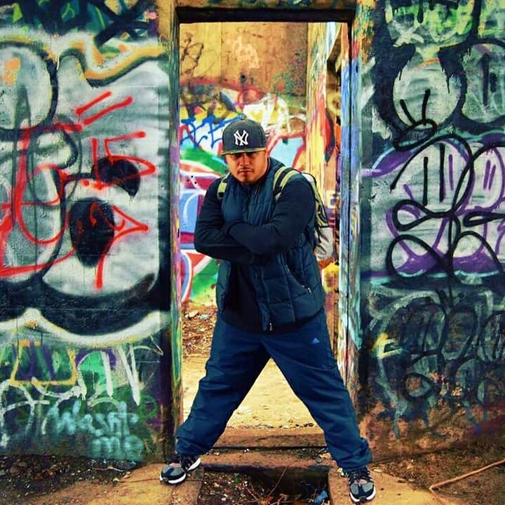 PORTRAIT OF YOUNG MAN STANDING AGAINST GRAFFITI