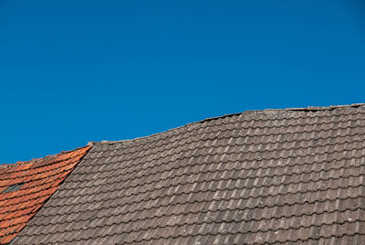 Low angle view of building roof against clear blue sky