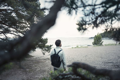 Rear view of wonderlust man standing at lakeshore