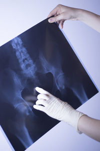 Cropped hands of woman holding x-ray image against wall