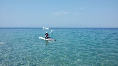 Woman paddleboarding on sea against clear sky