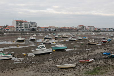 Boats moored at harbor against sky in city