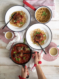 Cropped hands of woman serving spaghetti with meatballs on table