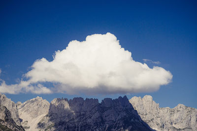 Low angle view of snowcapped mountains against blue sky