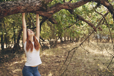 Young woman standing by tree